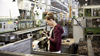 Intern inspecting part from assembly line