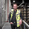 Portraitbild von Dirk Siebert. Links von ihm ist eine Temponox-Installation, während man rechts über zahlreiche Krombacher-Kisten schauen kann. 