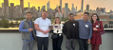 Visitors posing for a picture in the VEC balcony with the NYC skyline in the background