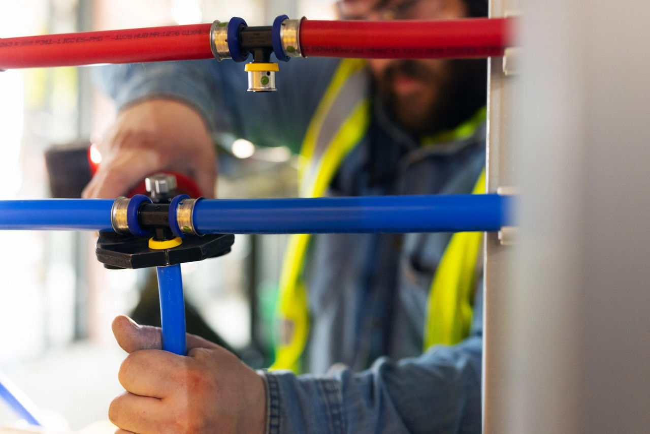 Plumber pressing a PureFlow to connect a blue pex line